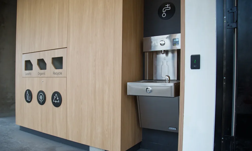 Elkay EZH2O Vandal-Resistant Drinking fountain & bottle filling station positioned next to smart recycle facility.