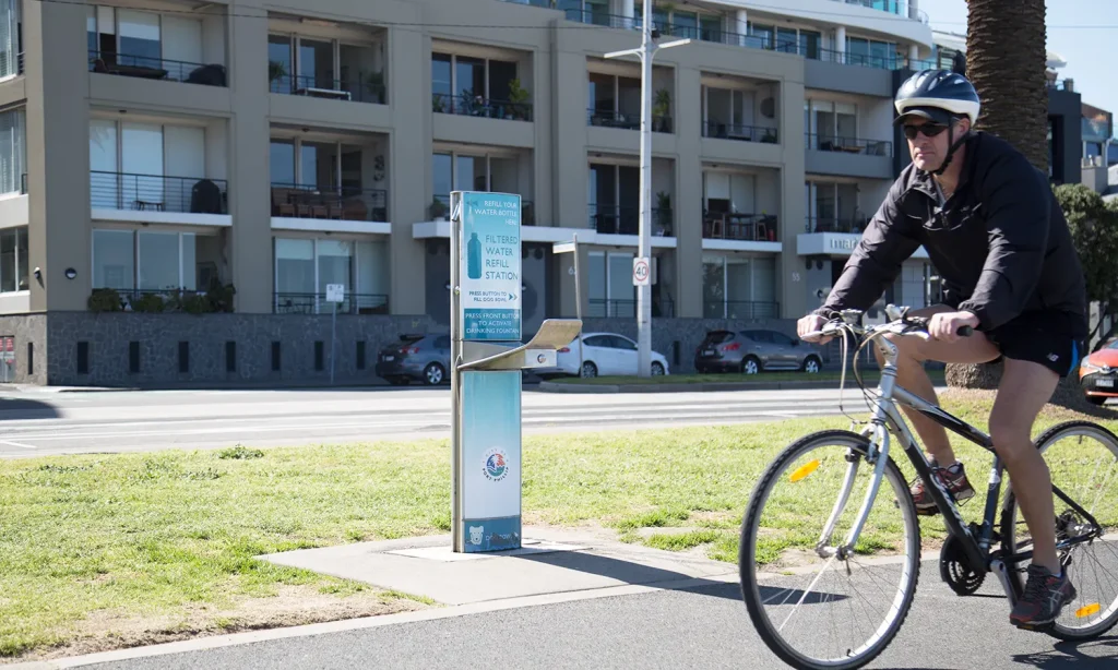 Cyclist riding on bike next to drinking fountain in Port Phillip beach