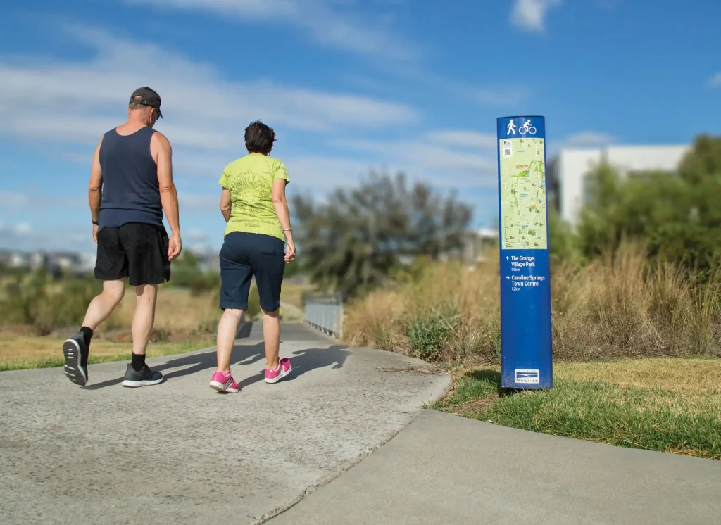 Two people walking beside a Wayfinding Signage in Melton City Council