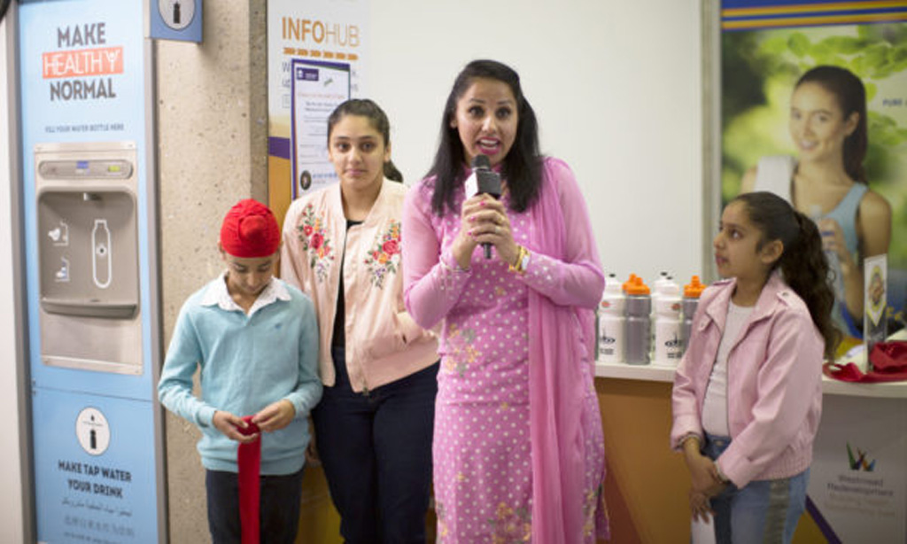 Reema Randhawa with her family speaks on the importance of teaching healthy habits to children beside an Elkay Water Bottle Refilling Station