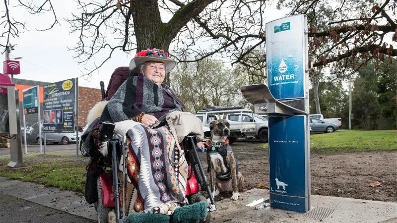Michelle Mc Donald in a wheelchair standing beside of the new Aquafil Drinking Water Fountain in Lilydale