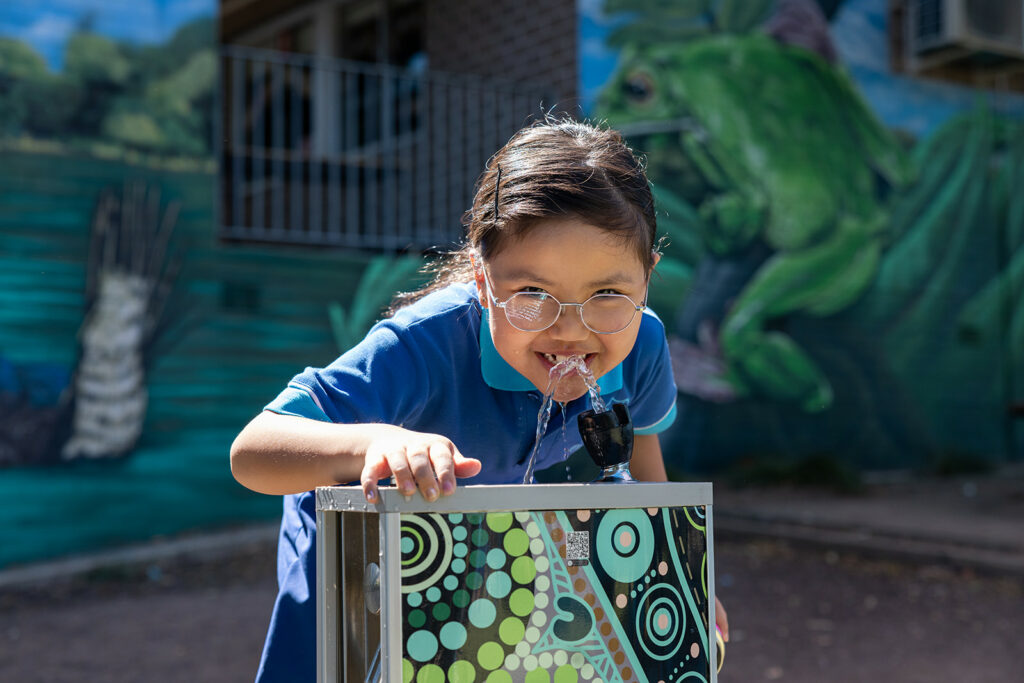 Student from Berala Public School enjoying drinking on their Aquafil Drinking Fountain, that is upgraded with their School Aboriginal Art.