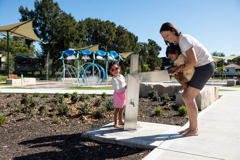 A family drinking on Aquafil Bold Drinking Fountain for Open Spaces and Playgrounds