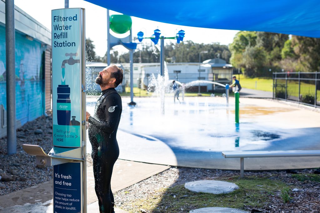 a guest at Holiday Haven Culburra Beach using Aquafil FlexiShower, an outdoor shower for public spaces and resorts.