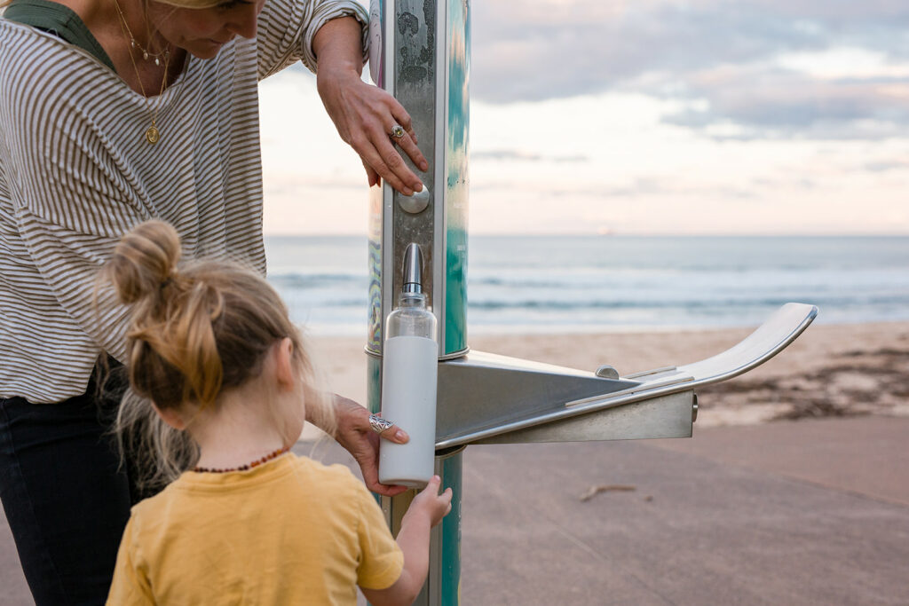 A woman and her daughter happily refilling their drinking water bottles at an Aquafil FlexiFountain Drinking Water Station installed at Pinecourt Reserve in Austinmer to East Corrimal Beach