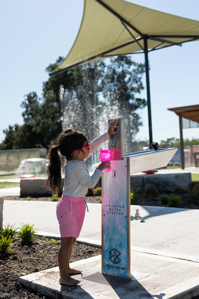 A child refilling her water bottle at an Aquafil Bold Drinking Fountain installed at The Greenacre Splash Park 