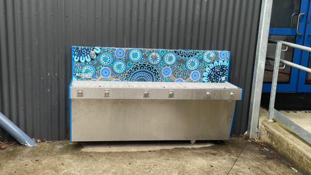 The Civiq Hydrobank School Drinking Trough adorned with Aboriginal Blue Art, replacing the outdated unit at Boronia, Victoria, bringing a blend of heritage and modernity.