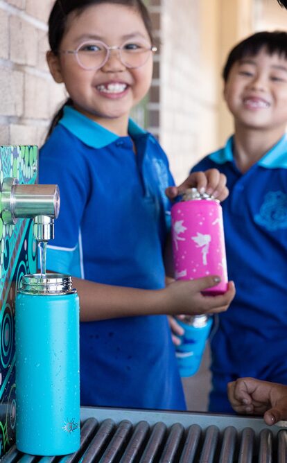 Photo of smiling students filling their water bottles at a school water station, the Aquafil Hydrobank, making it easy and fun to stay hydrated at school.